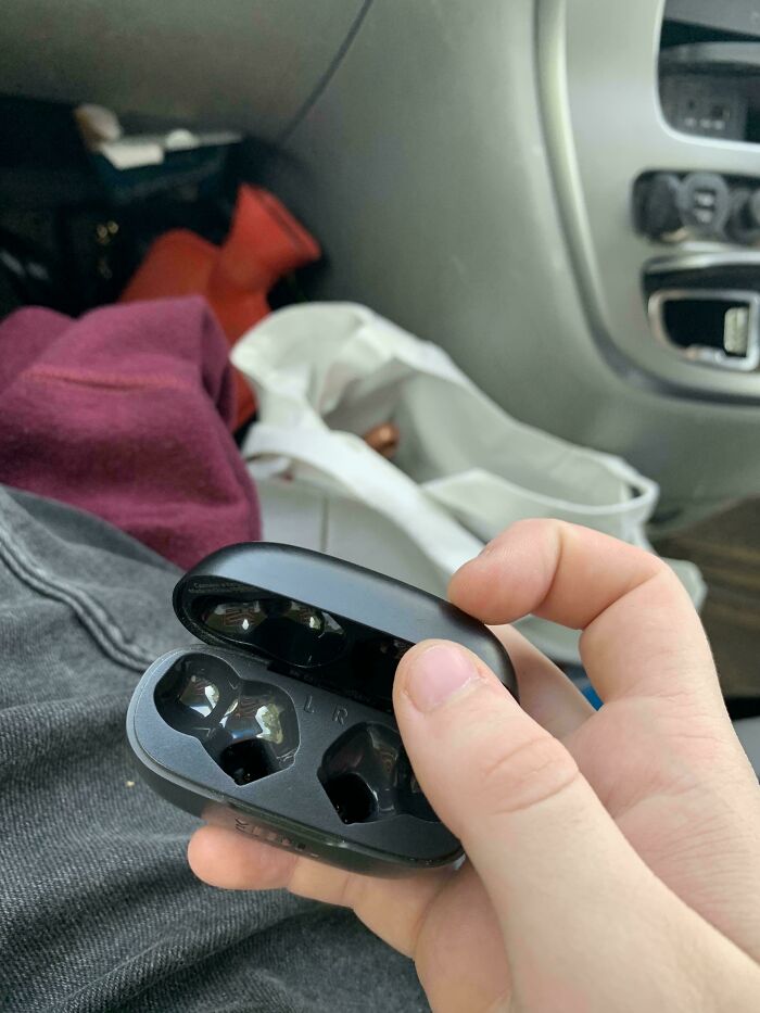 Auriculares inalámbricos vacíos en mano dentro de un coche, ejemplo de fotos de vacaciones que no salieron como se esperaba.