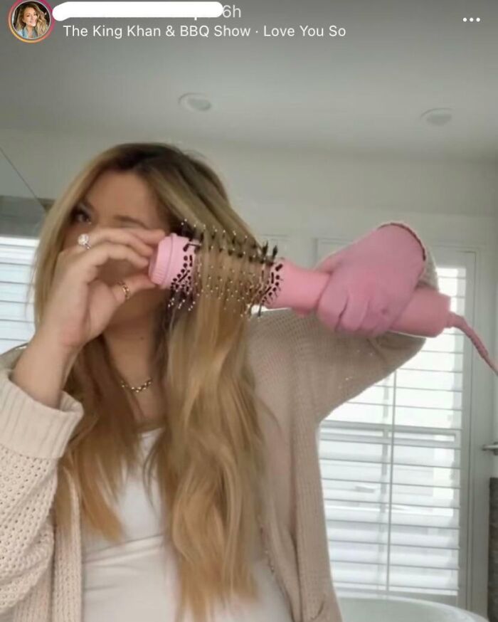 Influencer usando un cepillo de aire caliente rosa, ejemplo de decisiones de influencers que causan risas en todo el mundo.