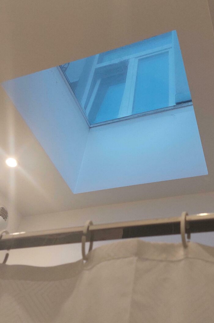 Ventana de techo reflejando un edificio en una foto de vacaciones que no salió como se esperaba.