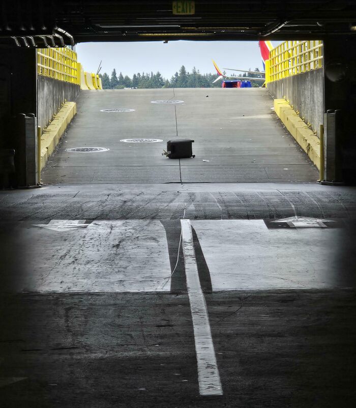 Foto inesperada en vacaciones con objeto caído en rampa de estacionamiento vacío y luz natural al fondo.