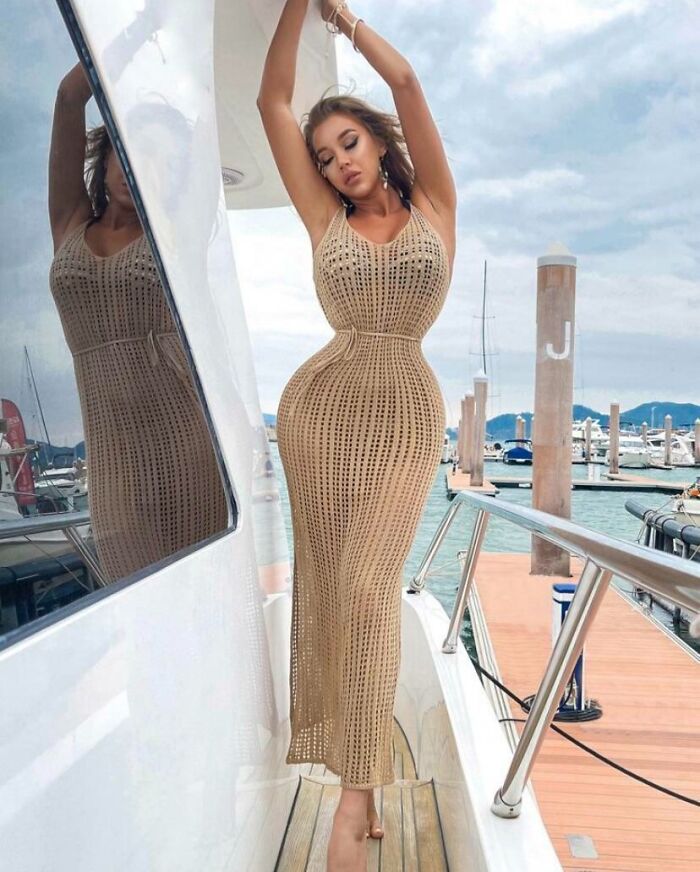 Influencer posando en vestido beige en yate, ilustrando decisiones tontas que hicieron reír al mundo.