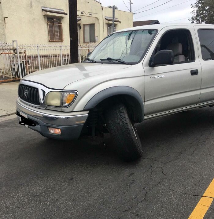 Camioneta con rueda delantera rota en calle, ejemplo de fotos inesperadas de vacaciones y momentos sorprendentes.
