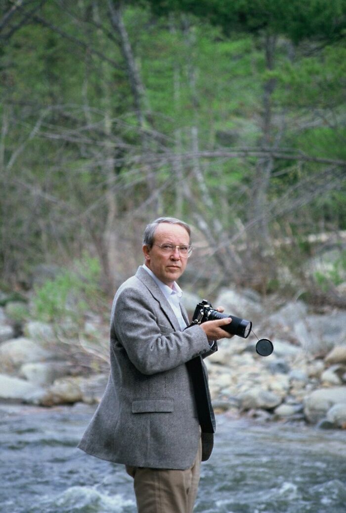 Hombre con cámara fotográfica en un río rodeado de naturaleza, capturando momentos de una época diferente. Hombre con cámara fotográfica en un río rodeado de naturaleza, capturando momentos de una época diferente.