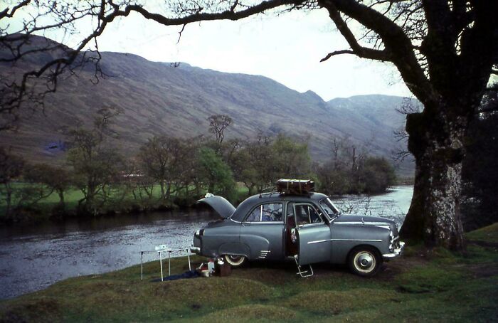 Coche clásico estacionado junto a un río en un paisaje montañoso, disfrutando de un tiempo diferente y relajado. Coche clásico estacionado junto a un río en un paisaje montañoso, disfrutando de un tiempo diferente y relajado.