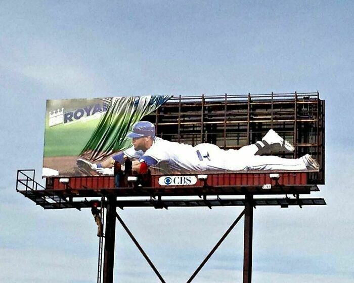 Valla publicitaria creativa con jugador de béisbol en posición de deslizamiento, ejemplo perfecto de carteles divertidos y brillantes.