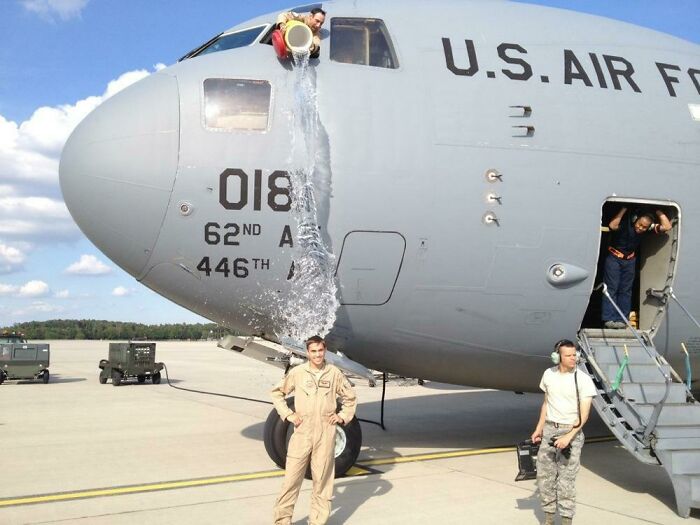 Personal militar junto a un avión mientras cae agua encima justo antes de que ocurra un accidente divertido capturado en la foto.