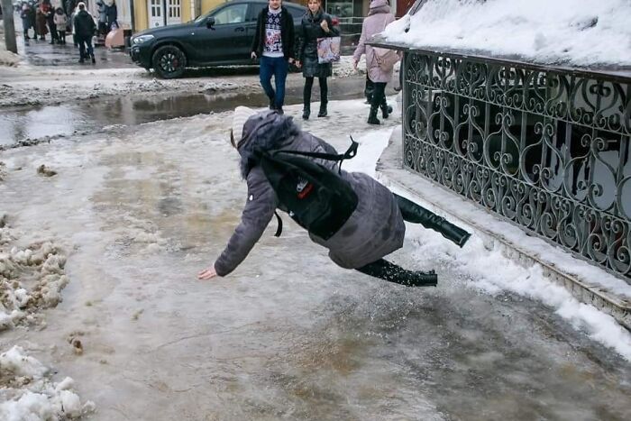 Persona resbalando en hielo en la calle, capturando el instante antes del desastre de forma divertida.