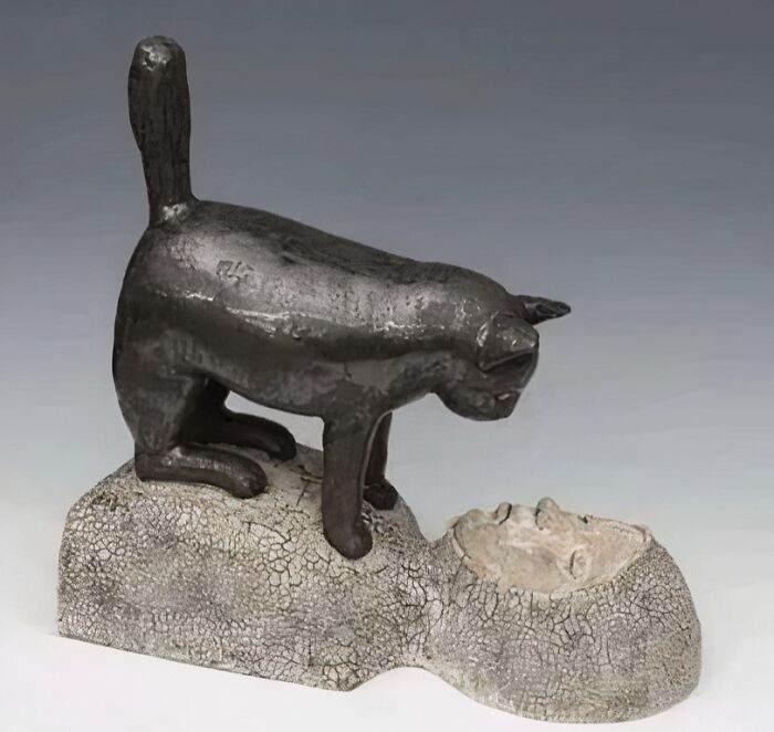 Escultura medieval de un gato curioso sobre la cabeza de una figura humana, imagen divertida de gatos medievales.