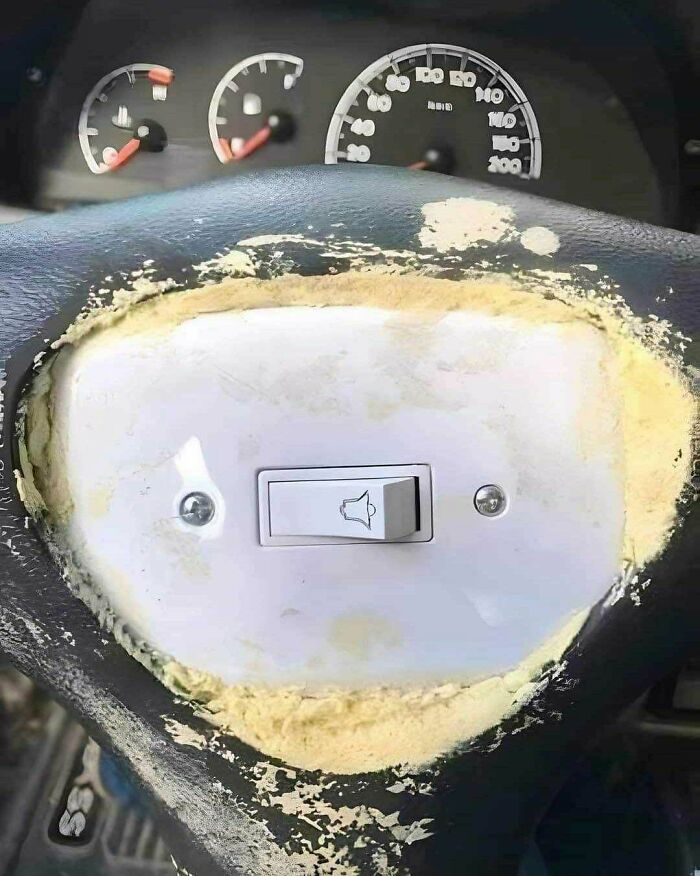 Interruptor de timbre instalado en volante con acabado irregular, mostrando divertidos fallos de construcción en el vehículo.
