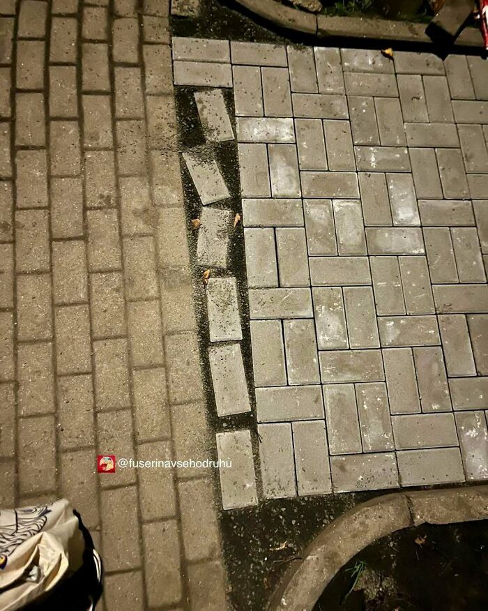 Imperfección en pavimento con fallos de construcción y adoquines mal colocados causando contraste visible.