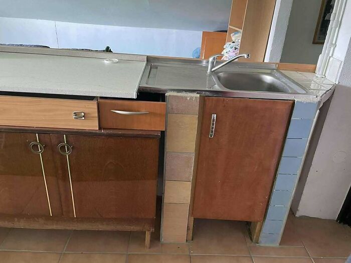 Mueble de cocina con fallos de construcción visibles, espacio irregular y soporte improvisado con bloques de cemento.