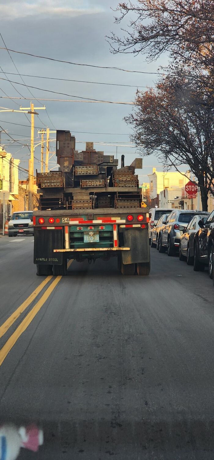 Camión transportando carga metálica peligrosa sin medidas de seguridad adecuadas en carretera urbana concurrida.