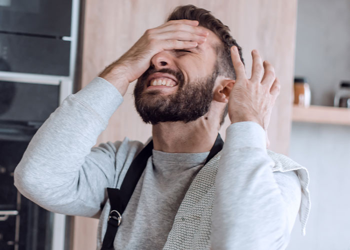 Hombre con expresión de frustración y las manos en la cabeza, mostrando incredulidad ante una situación poco inteligente.