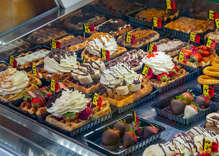 Variedad de postres con crema, fresas y chocolate en vitrina, mostrando selección deliciosa para todos los gustos.