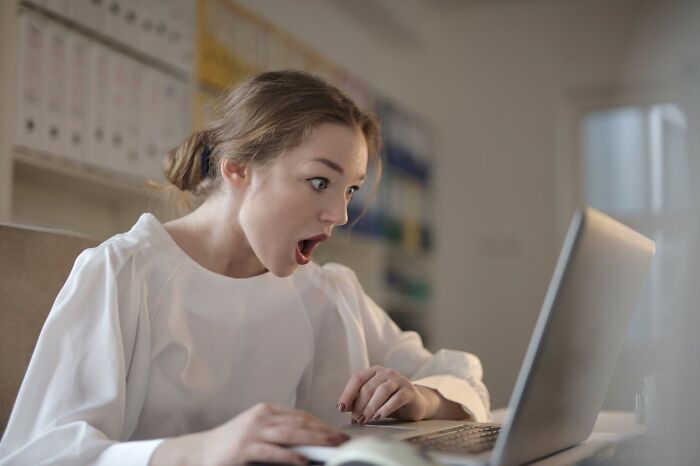 Mujer sorprendida frente a su computadora, mostrando emoción en un momento inesperado que cambió su mundo.