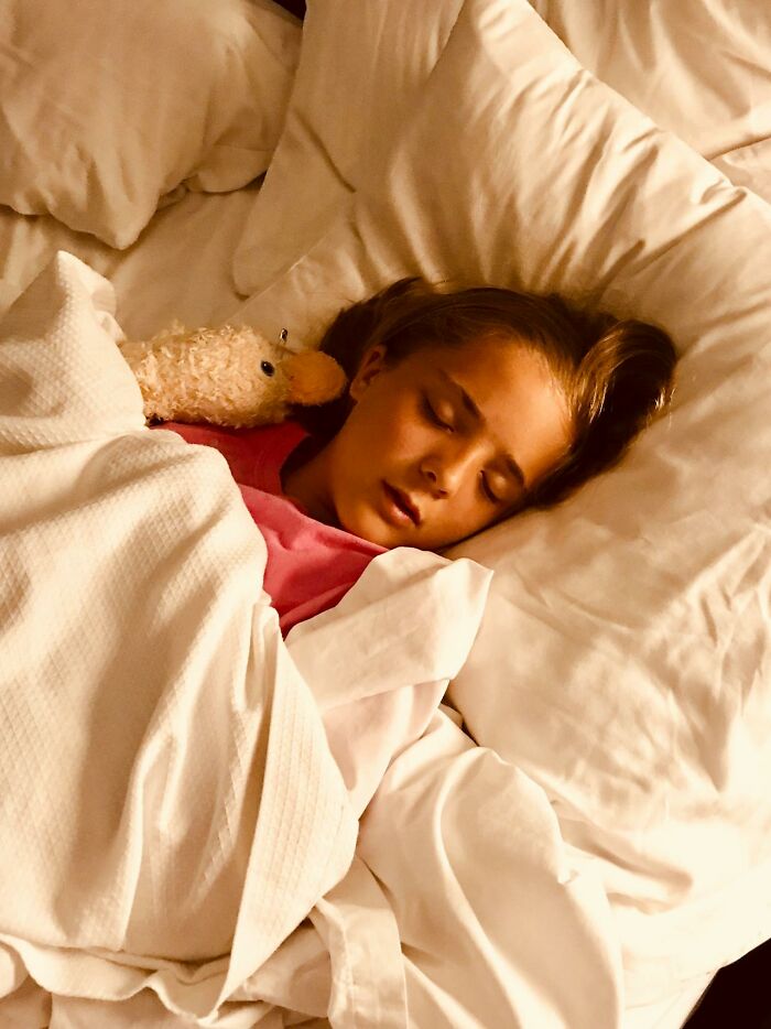 Niña durmiendo con peluche en cama, mostrando inocencia antes de un accidente que cambió la vida accidentalmente.