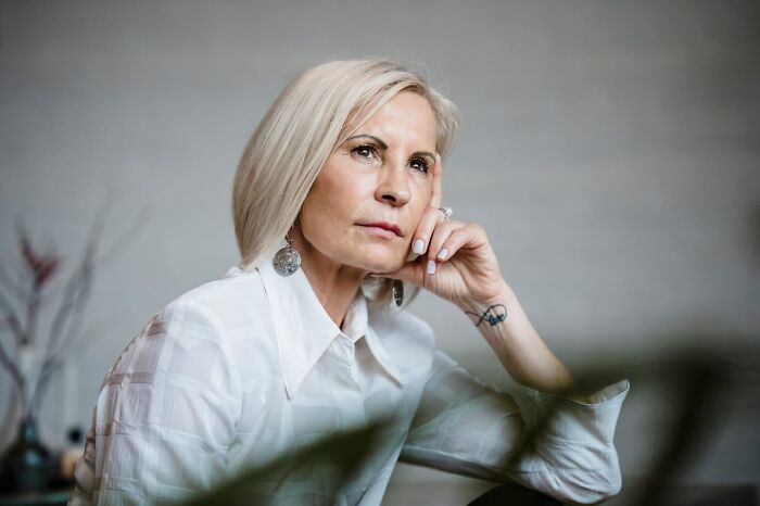 Mujer madura pensativa reflexionando sobre cómo accidentalmente se convirtió en la razón de que el mundo de alguien colapsara.
