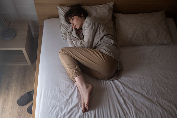 Mujer acostada en cama en postura fetal mostrando miedo y ansiedad relacionada con Nutty Putty Cave. Mujer acostada en cama en postura fetal mostrando miedo y ansiedad relacionada con Nutty Putty Cave.