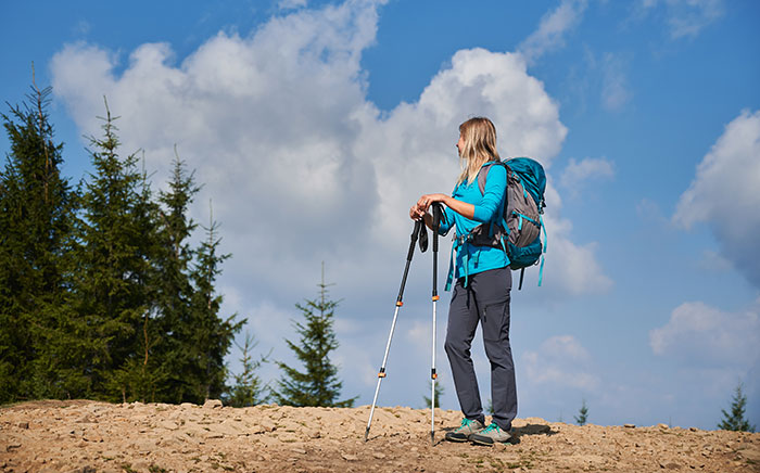 Mujer con mochila y bastones de senderismo en paisaje montañoso, inspirada por historias de Nutty Putty Cave. Mujer con mochila y bastones de senderismo en paisaje montañoso, inspirada por historias de Nutty Putty Cave.