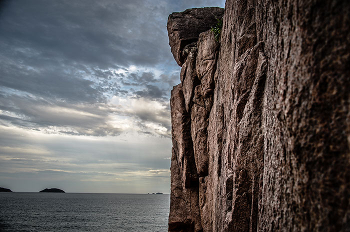 Acantilado rocoso junto al mar con cielo nublado, evocando la atmósfera de Nutty Putty Cave y sus relatos inquietantes. Acantilado rocoso junto al mar con cielo nublado, evocando la atmósfera de Nutty Putty Cave y sus relatos inquietantes.