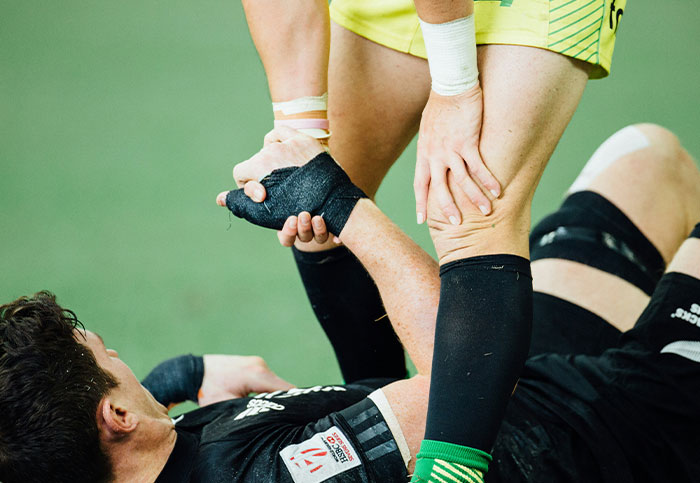 Jugador de rugby ayudando a compañero lesionado, símbolo del arrepentimiento y la culpa por arruinar vidas según confesiones.