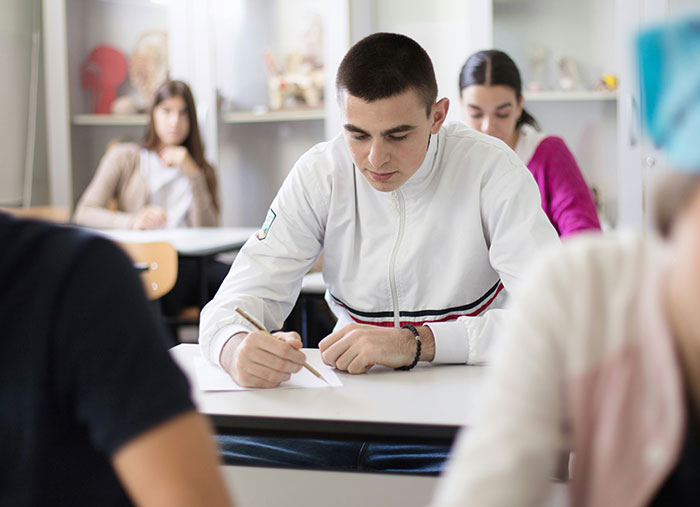Joven concentrado escribiendo en clase, reflejando sentimientos de culpa y confesar arruinar la vida de alguien.