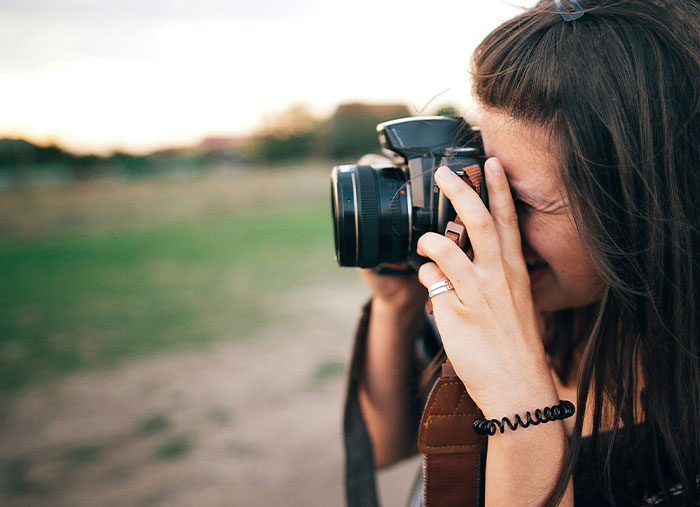 Mujer joven tomando fotos al aire libre, representando personas que confiesan arruinar la vida de alguien.