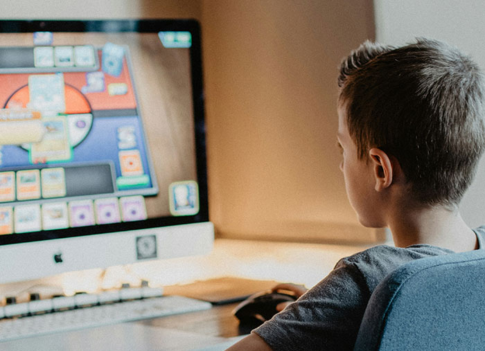 Niño concentrado jugando en computadora, reflejando emociones relacionadas con arruinar la vida de alguien y arrepentimiento.