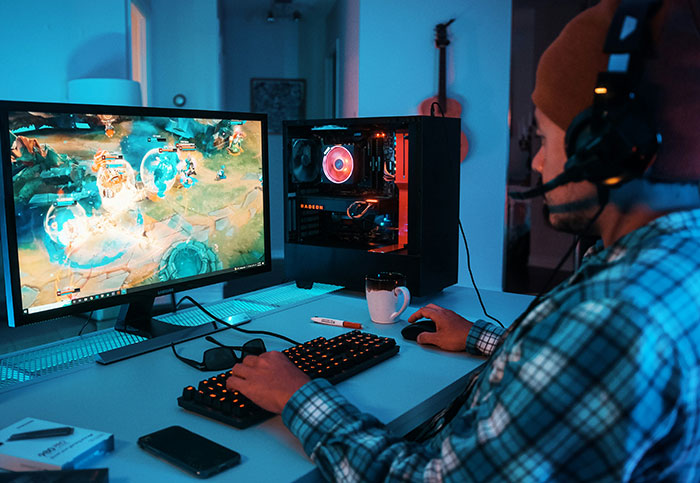 Persona jugando en PC con auriculares, reflejando confesiones sobre arruinar la vida de alguien en internet.