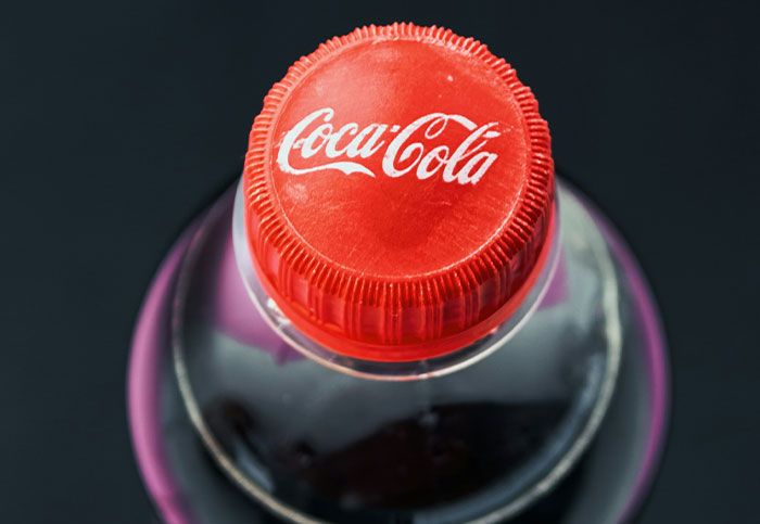 Tapón rojo de botella de Coca-Cola con fondo negro, ilustrando el concepto de arruinar la vida de alguien.
