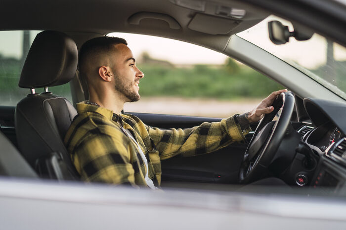 Hombre sonriente conduciendo un coche relacionado con historias de terror inolvidables de médicos y enfermeras.
