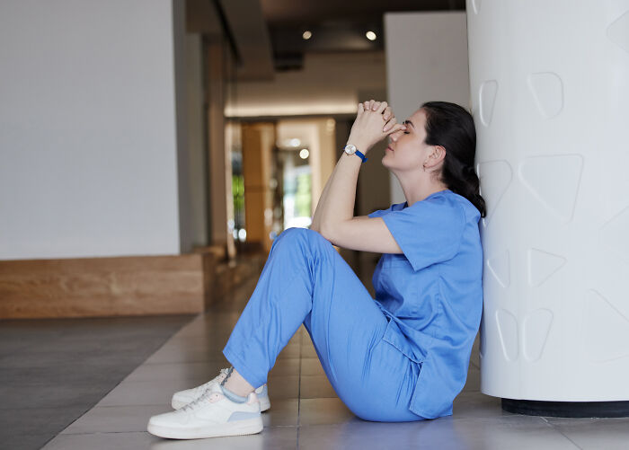 Enfermera preocupada en pasillo del hospital, reflejando estrés y momentos de horror vividos en su labor médica.