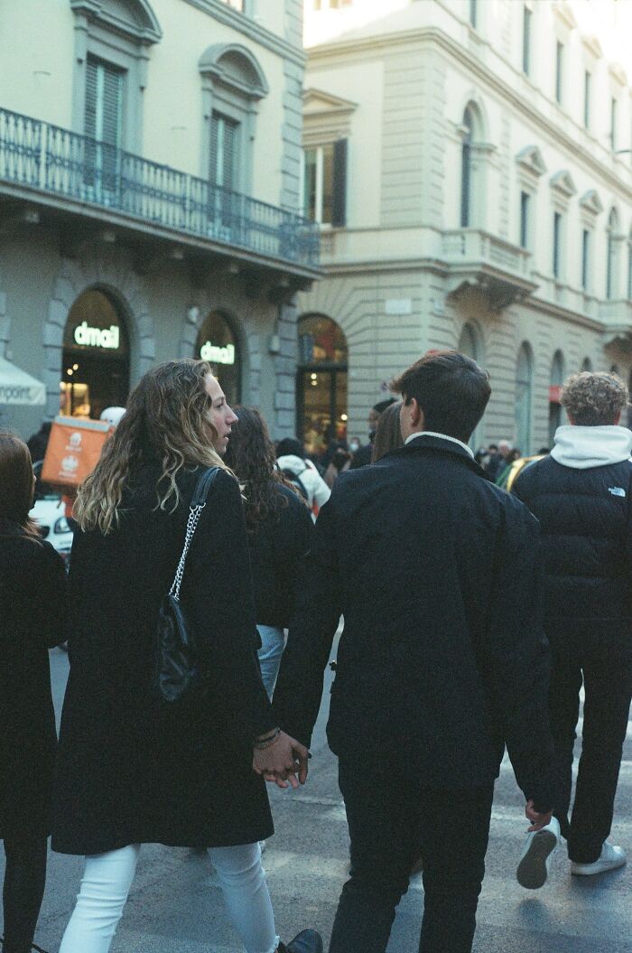Pareja caminando de la mano en una calle concurrida, reflejando el momento en que alguien accidentalmente arruina el mundo de otro.