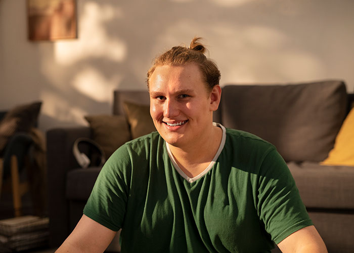 Hombre sonriendo en sala iluminada por la tarde, representando personas que mintieron y sus consecuencias posteriores.