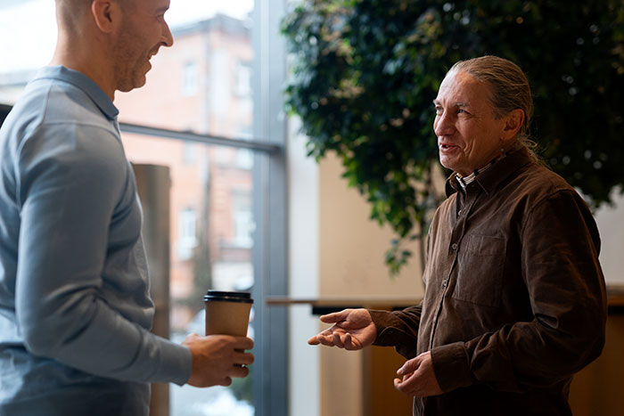 Hombres conversando en interior, ilustrando consecuencias que tuvieron para otras personas por mentiras reveladas después.