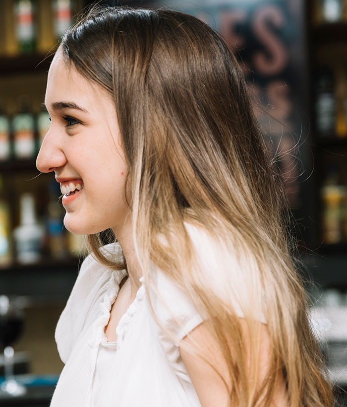 Joven sonriendo en un bar, ilustrando las consecuencias de mentiras y sus efectos en otras personas.
