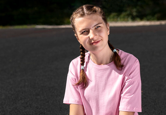 Joven con trenzas y camiseta rosa sonriendo, representando las consecuencias que tuvieron las mentiras para otras personas.