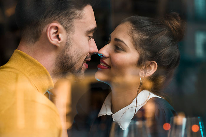 Pareja mirándose de cerca en un café, ilustrando las consecuencias que tuvo mentir para otras personas.