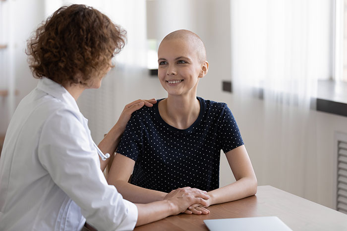 Paciente con cáncer recibiendo apoyo emocional de doctora, mostrando consecuencias que tuvieron las mentiras en otras personas.