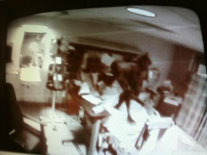 Fotografía real inexplicable tomada en hospital con figura oscura sobre paciente en una cama, imagen borrosa y misteriosa.