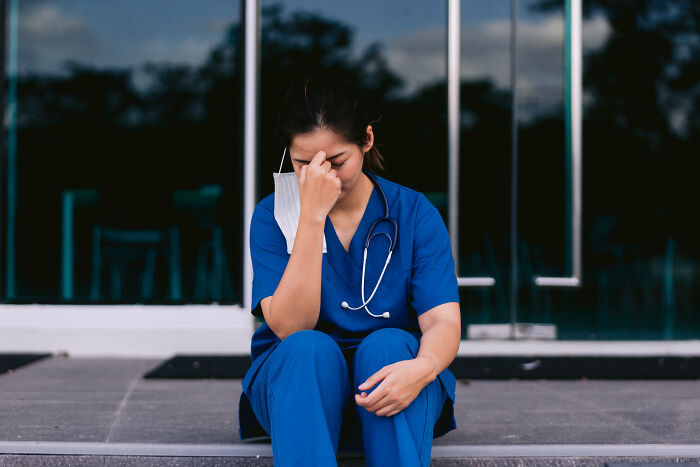 Enfermera en uniforme azul con estetoscopio mostrando fatiga y estrés tras historias de horror inolvidables en medicina.