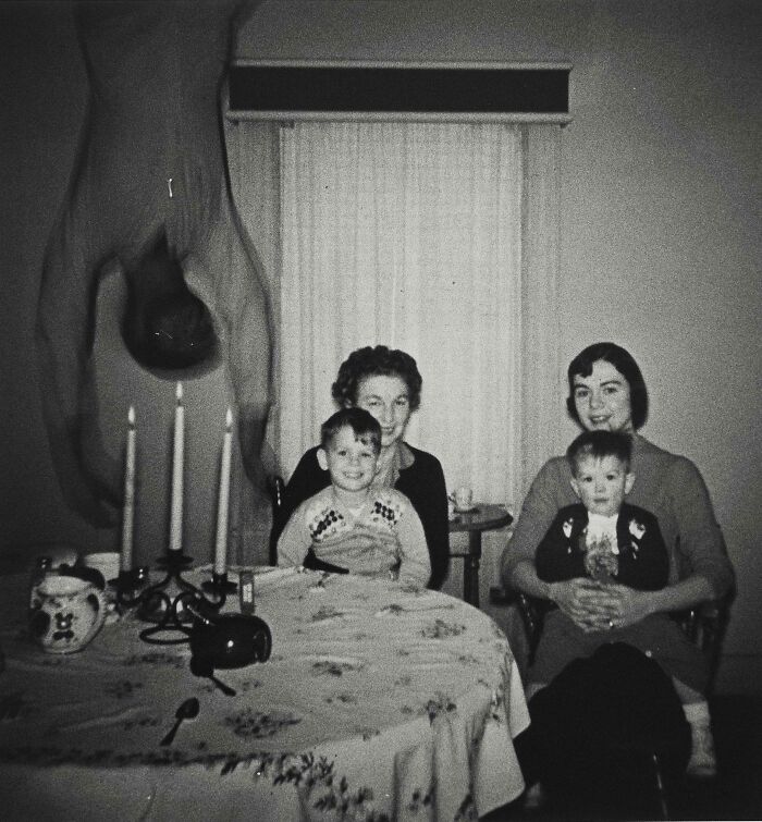 Foto en blanco y negro de una familia y figura humana inexplicable levitando, imagen real sin explicación hasta hoy.