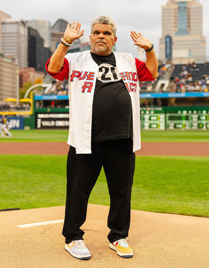 Hombre en estadio de béisbol con camiseta de Puerto Rico, destacando altura real de estrellas masculinas sorprendentes.