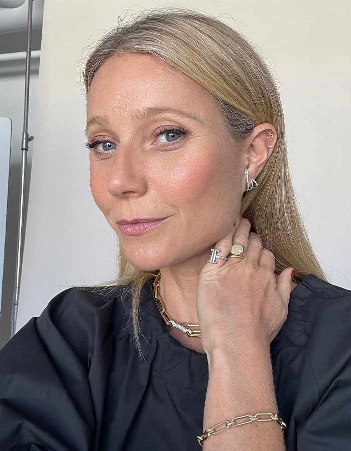 Mujer celebridad rubia con joyas y blusa negra posando para foto mostrando falta de comprensión de la vida normal.