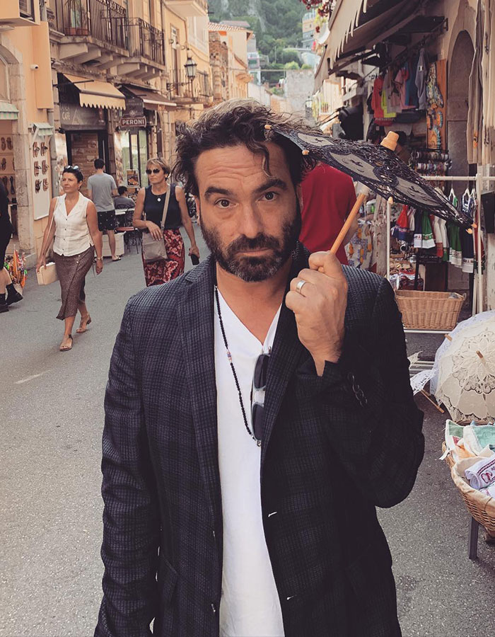 Hombre con chaqueta oscura y sombrilla negra en mercado callejero, relacionado con estrellas masculinas y su altura real sorprendente.