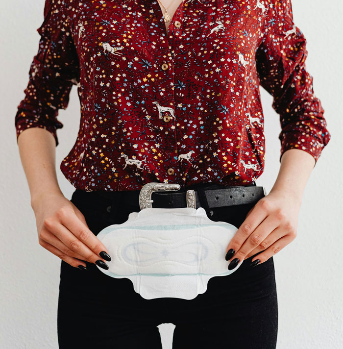 Persona sosteniendo una compresa femenina, ilustrando momentos hilarantes de desconocimiento común sorprendente.