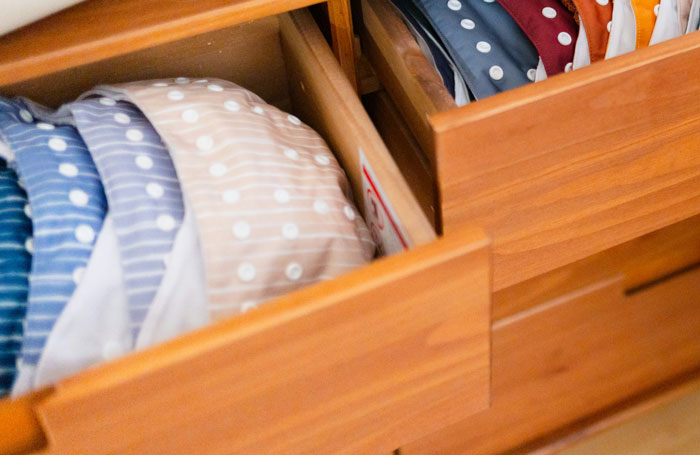 Cajones de madera organizados con ropa doblada y colores variados en un armario ordenado y limpio.