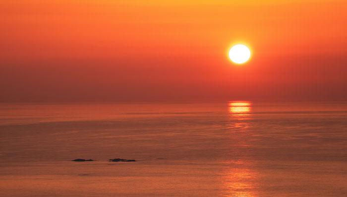 Atardecer sobre el océano con reflejo solar, simbolizando momentos hilarantes de desconocimiento común impactante.