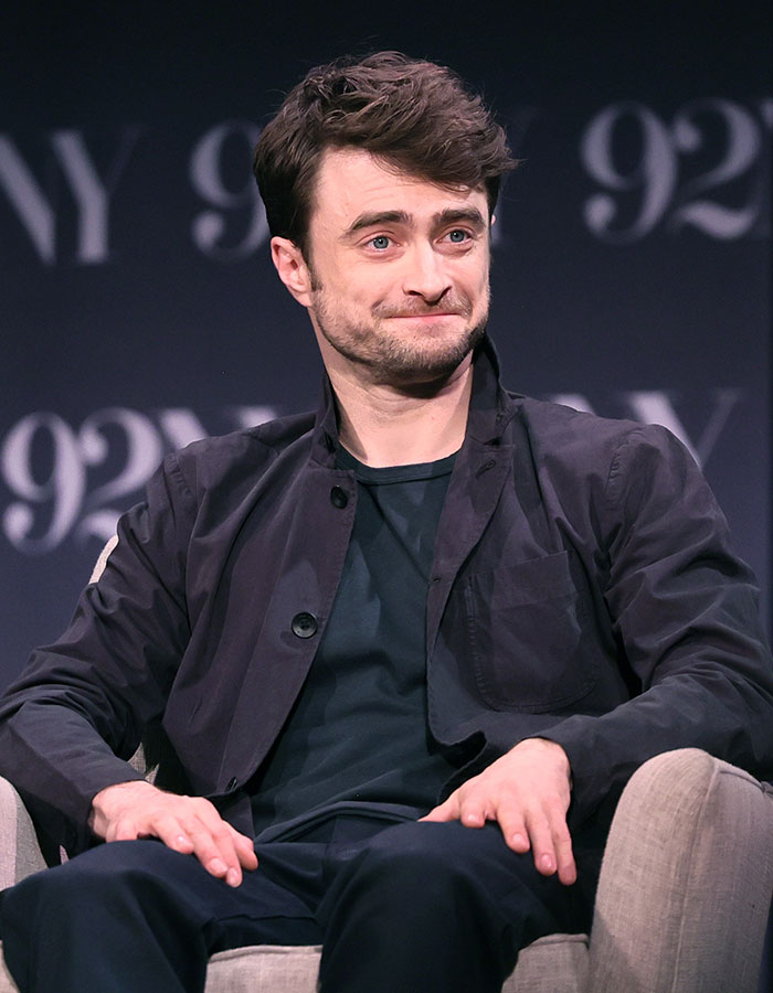 Actor masculino sentado en silla participando en entrevista, ilustrando estrellas masculinas y su altura real sorprendente.