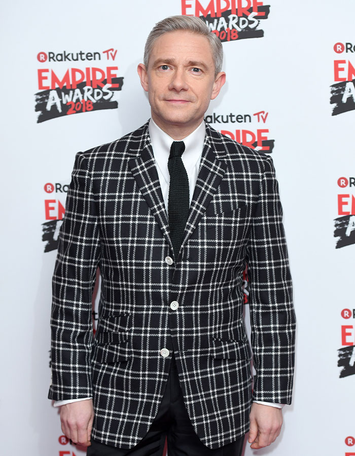 Actor masculino en evento Empire Awards 2018 con traje a cuadros negros y blancos, destacando altura sorprendente de estrellas masculinas.